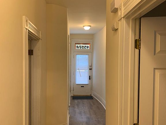 Hallway from kitchen, bathroom door on right, one bedroom door on left