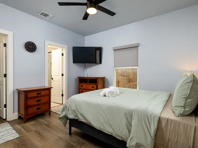 Primary bedroom with queen bed featuring a tv as well as an attached bathroom.