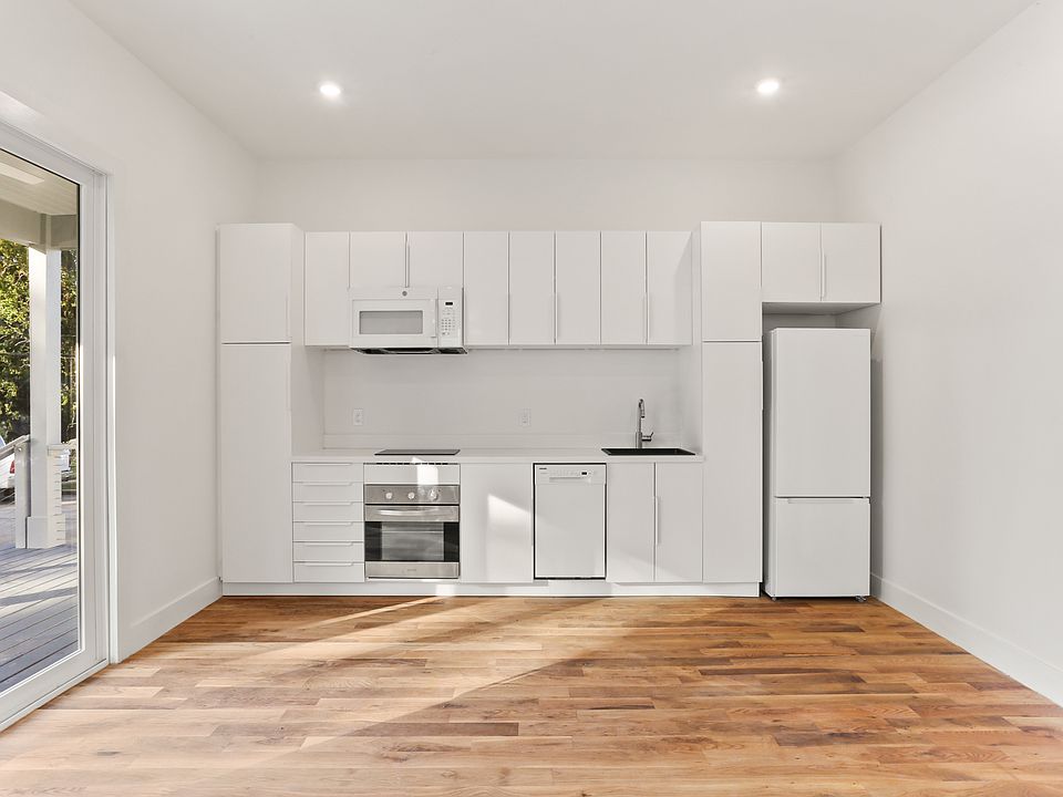 The modern kitchen features a pantry cabinet, stainless steel oven, induction cooktop, dishwasher and over the range microwave.