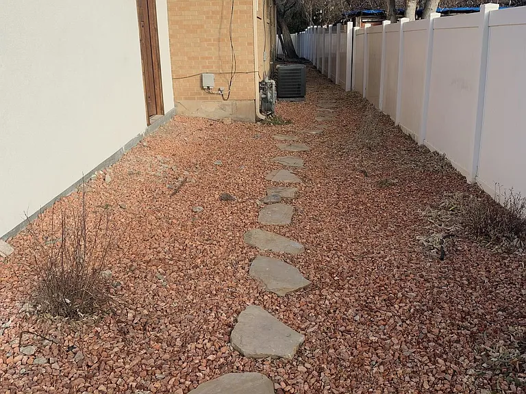Flagstone walkway and landscaping on east side of property leading from street, past the garage side door, to the unit entrance in the back