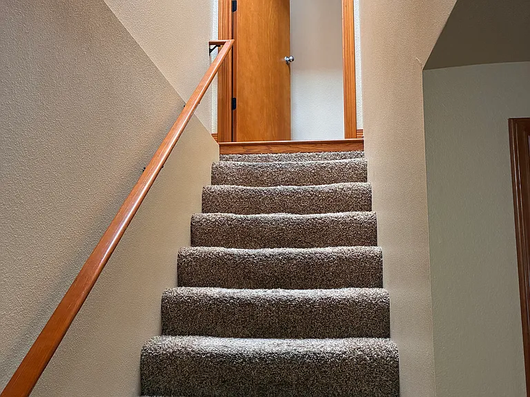Stairway from top level leading to additional living area and primary bedroom.