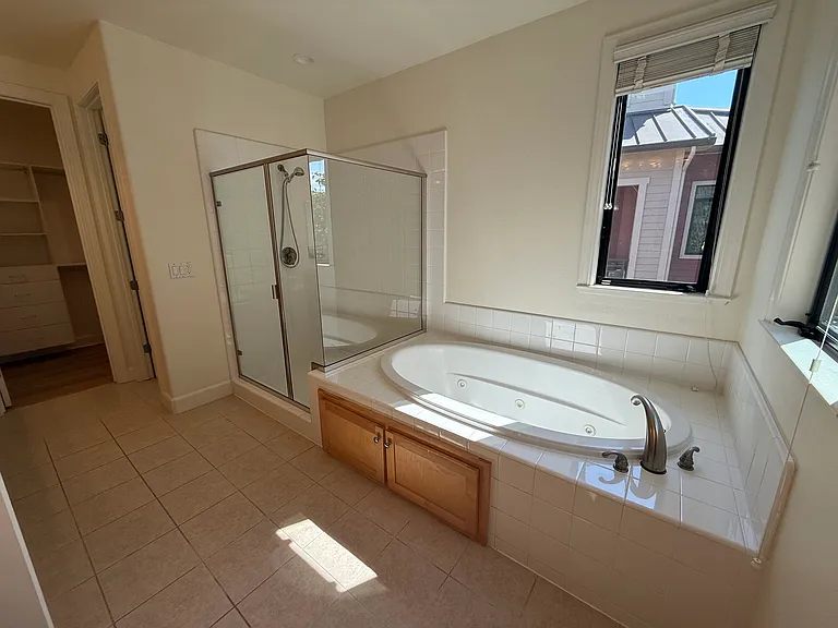 In-suite bathroom with 2 sinks, a whirlpool bathtub, a shower stall with glass enclosure and a second walk-in closet.