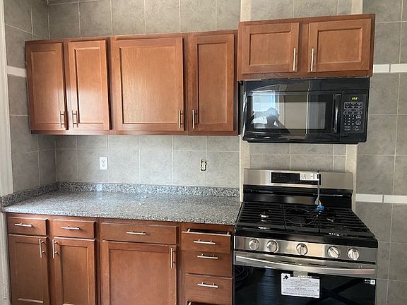 Partial view of kitchen - granite countertop, gas stove, microwave, new cabinets, ceramic tiles floors