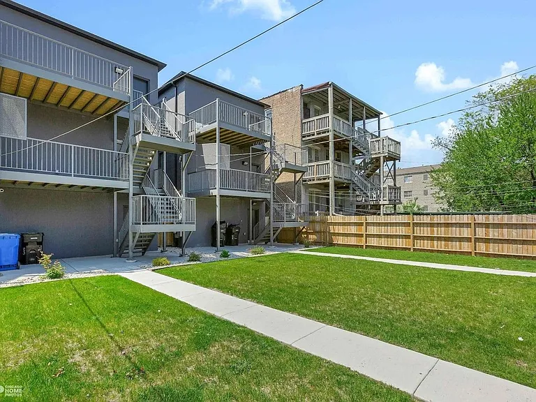 Backyard: Spacious shared fenced yard with lush green lawn, private decks on every level, and direct outdoor access