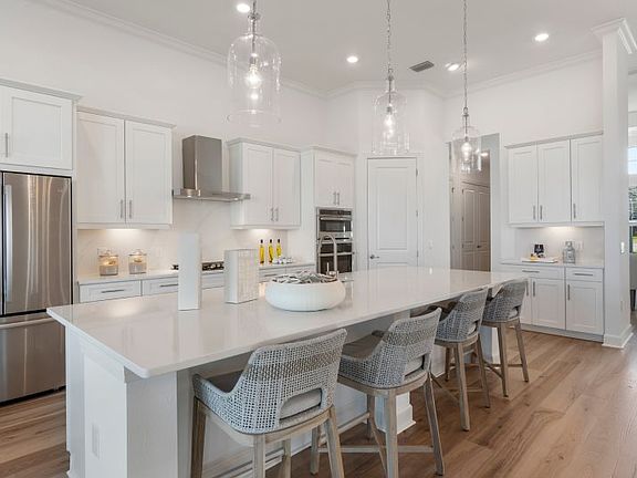 This elegant kitchen features an expansive island, stainless steal appliances and a design extending
