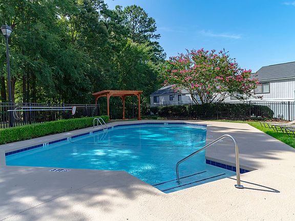 Outdoor swimming pool with chairs and umbrellas at Forest Ridge apartments for rent in North Macon, GA