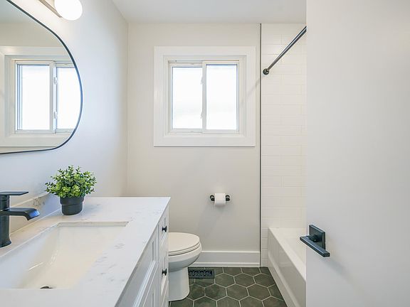 Bathroom - note solid wood vanity with white quartz counter top (6 drawers and 2 cupboards). Black hexagon tile flooring, black fixtures, brand new tub and tile surround. There is a deep and tall linen closet behind the bathroom door to store towels, toil