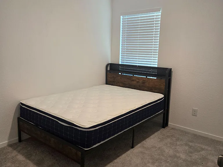 Private bedroom with a bed frame and window blinds, offering comfortable space for rest and easy furniture placement.