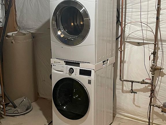 Stacked washer and dryer in utility room.