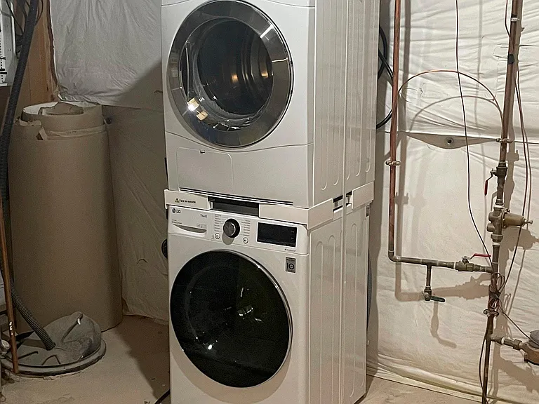 Stacked washer and dryer in utility room.