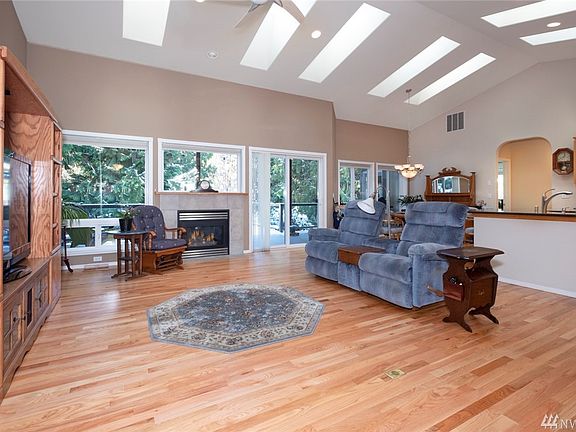 Entering the home from the foyer you are greeted by the wall of windows in the rear of the home showcasing the deck and beautifully landscaped yard.  Extensive use of skylights throughout the home bring light and visual warmth.