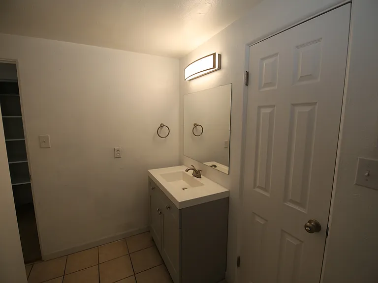 Bright and modern bathroom featuring a sleek vanity with under-sink storage, elegant tile flooring, and contemporary lighting.