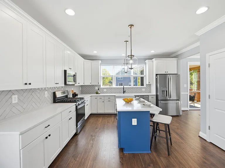 Chef's kitchen with island, farmhouse sink, herringbone backsplash, gas range, and breakfast nook.
