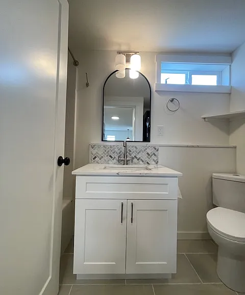 Newly completely renovated bathroom with large tub/shower, vanity with undermount sink in quartz counter with stone backplash. Corner toilet.