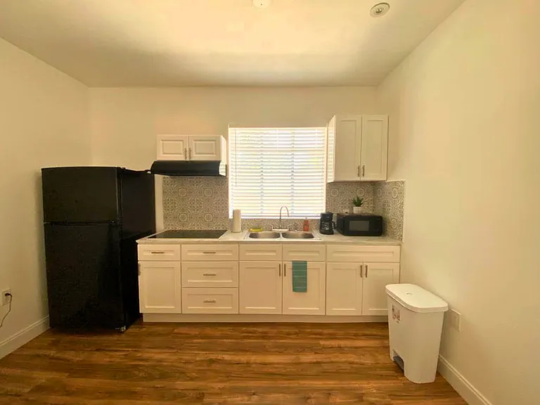 Fully equipped kitchen with stove, range hood, refrigerator, microwave, and coffee maker.