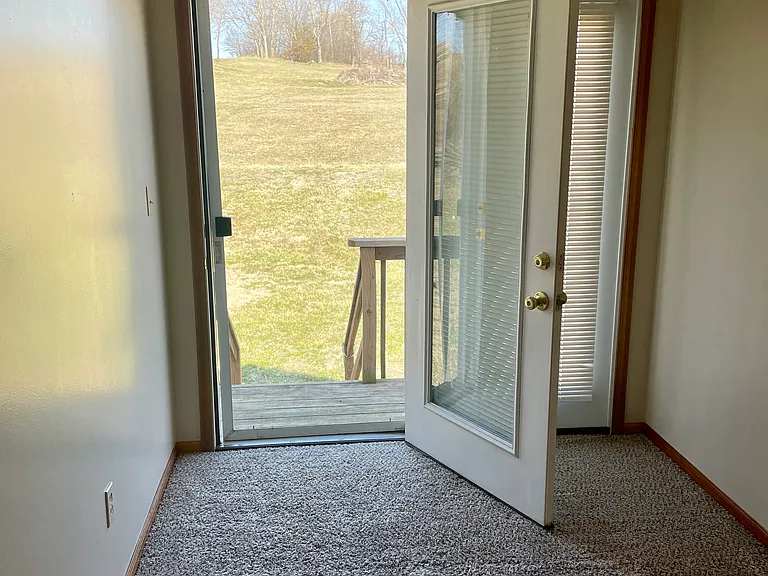 French doors off the Master bedroom with deck that looks out onto rolling hills in back
