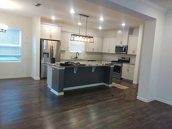 A picture of the kitchen taken today with the painters in the home. Fridge stays. Upgraded lighting throughout!