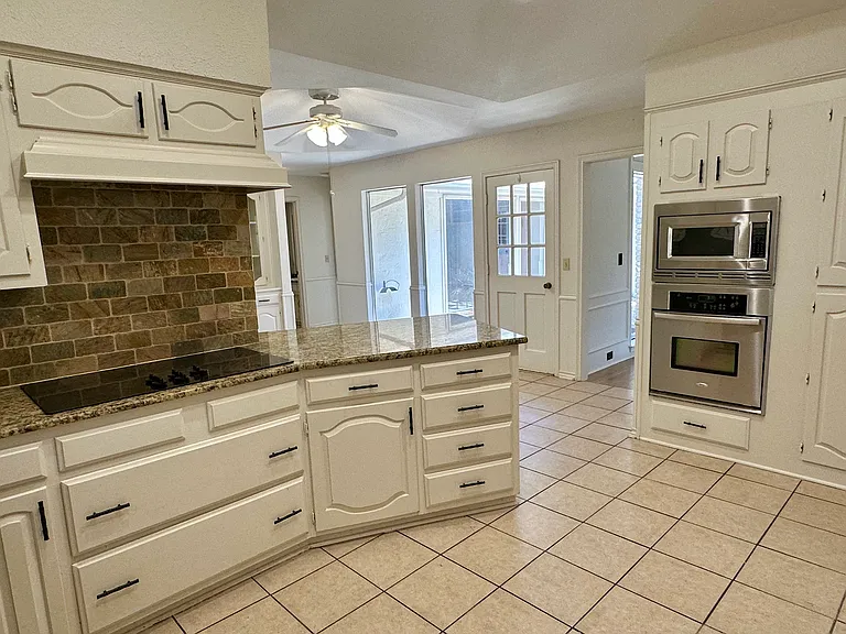 Kitchen with white cabinets, ceiling fan, stainless steel appliances, light tile patterned floors