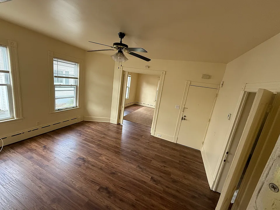Spacious living room with high ceilings and expansive windows that fill the space with natural light, complemented by a stylish ceiling fan.