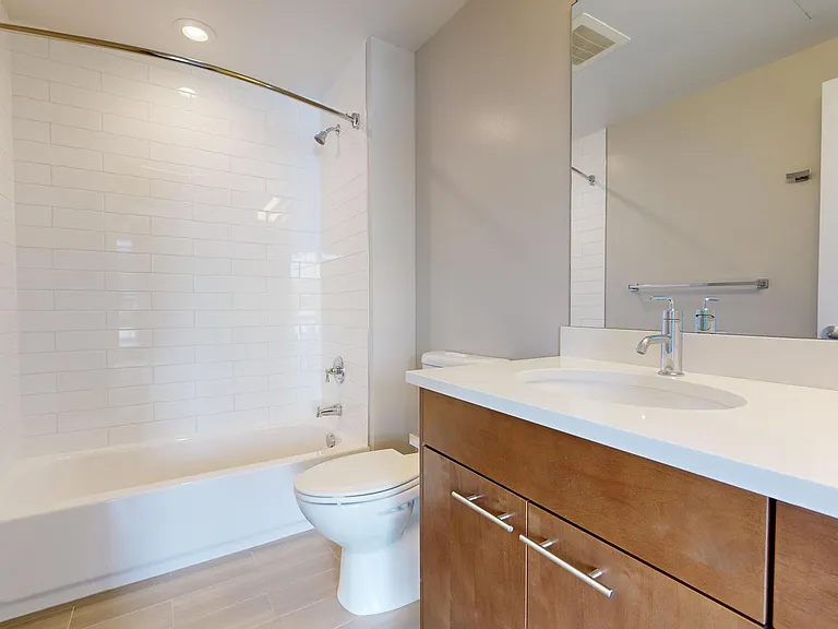 Apartment bathroom with wood-style flooring.