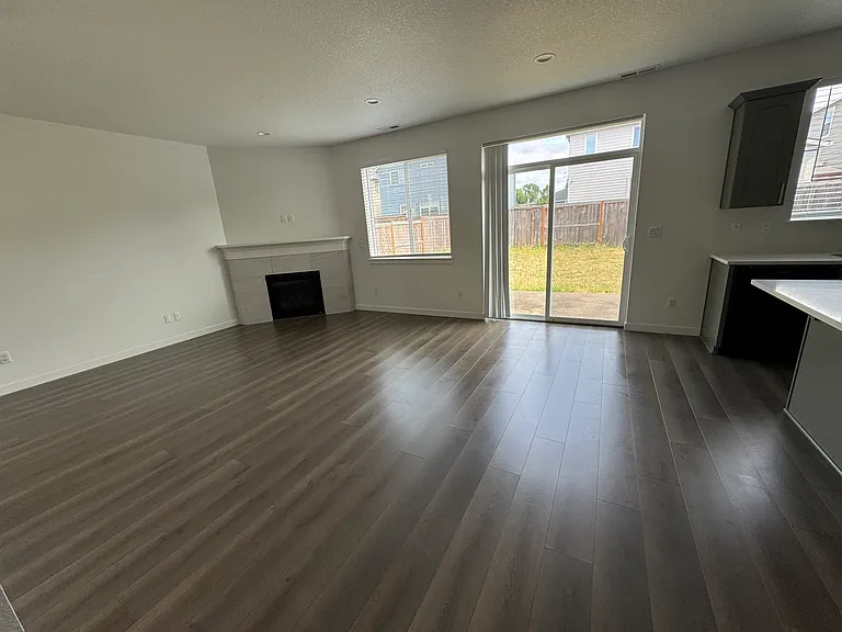 Living Room with gas fireplace, laminate wood floor, window blinds and sliding door to the backyard