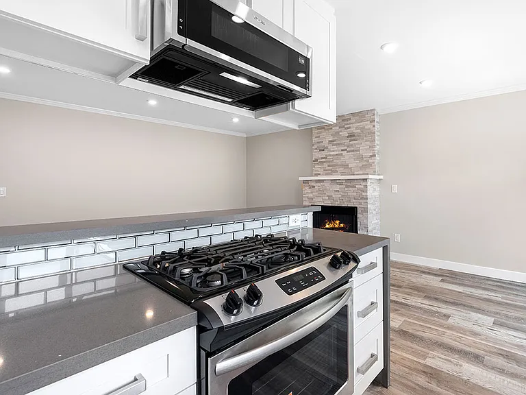 Blue tiled kitchen with stainless steel oven, fridge, dish washer, and fixtures.