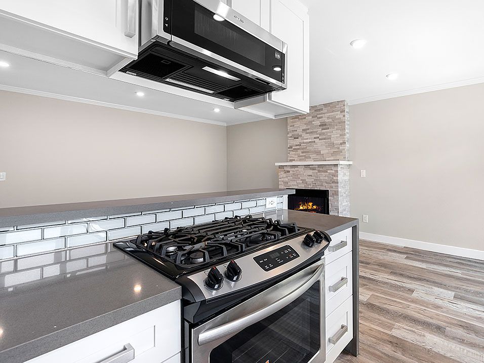 Blue tiled kitchen with stainless steel oven, fridge, dish washer, and fixtures.