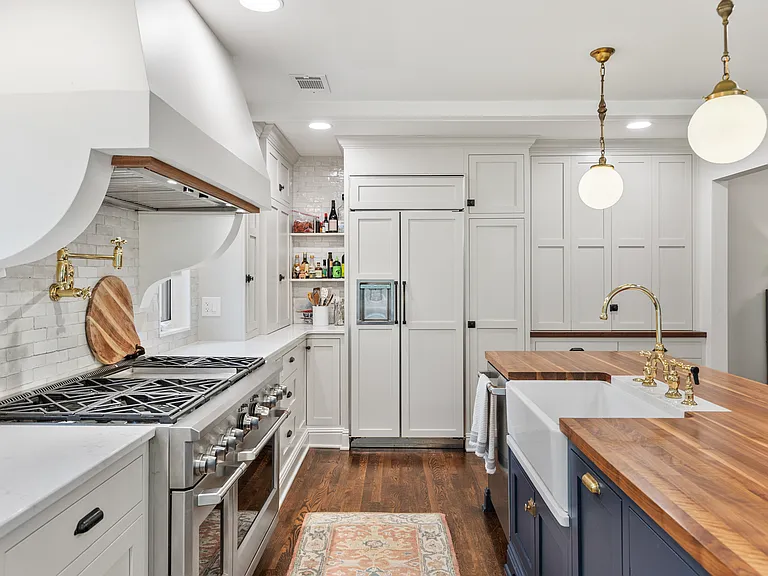 Recently updated state-of-the-art kitchen with a gas range, wall-mounted pot and kettle filler over the range, farm sink, and seating for four at the kitchen counter.