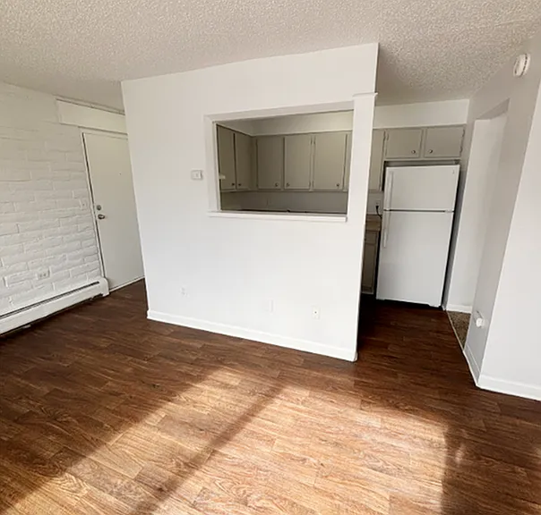 Bright apartment living space featuring elegant wood flooring, ample natural light, and a modern open kitchen layout.