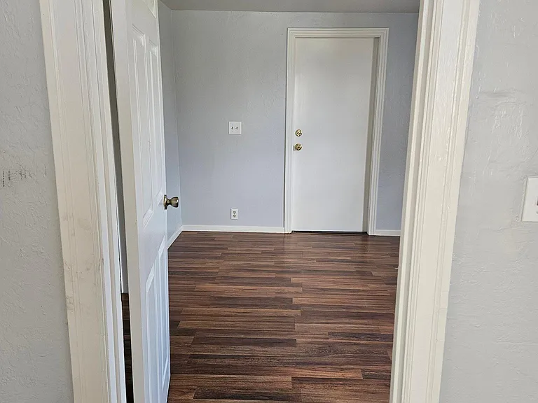 View into bedroom from living area. Back door opens to back yard and small covered porch.