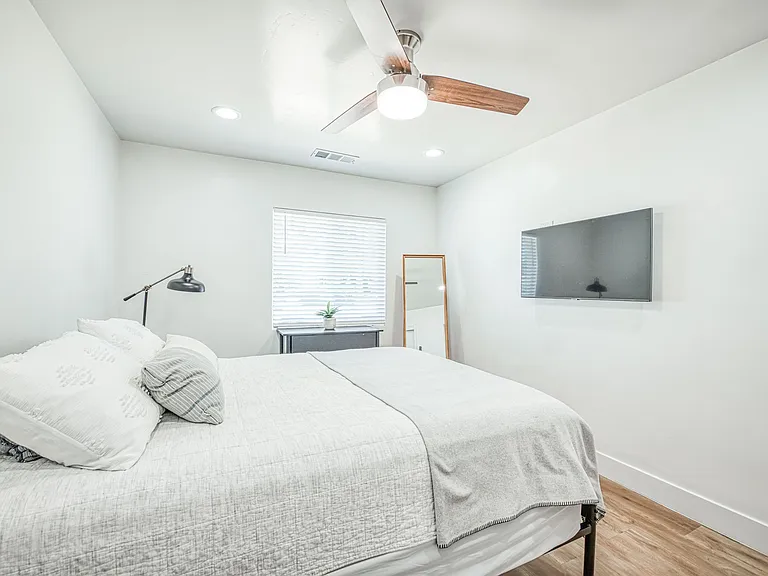 Bedroom with Cozy Bed. Ceiling Fan, Floor Mirror and Night Stand.