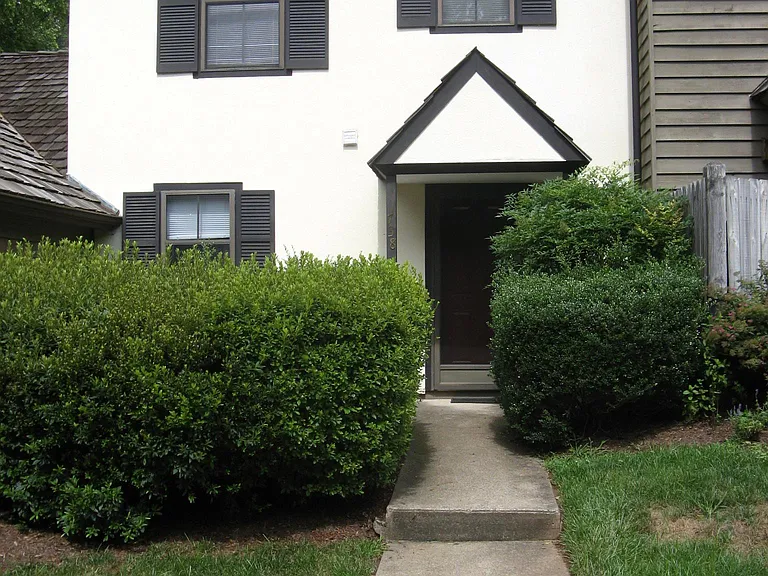 sitting patio behind tall azalea bushes to the left