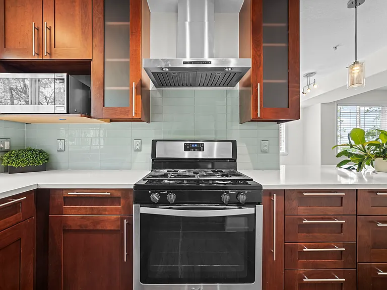 Gas range/oven, vent hood, microwave, glass tile backsplash.