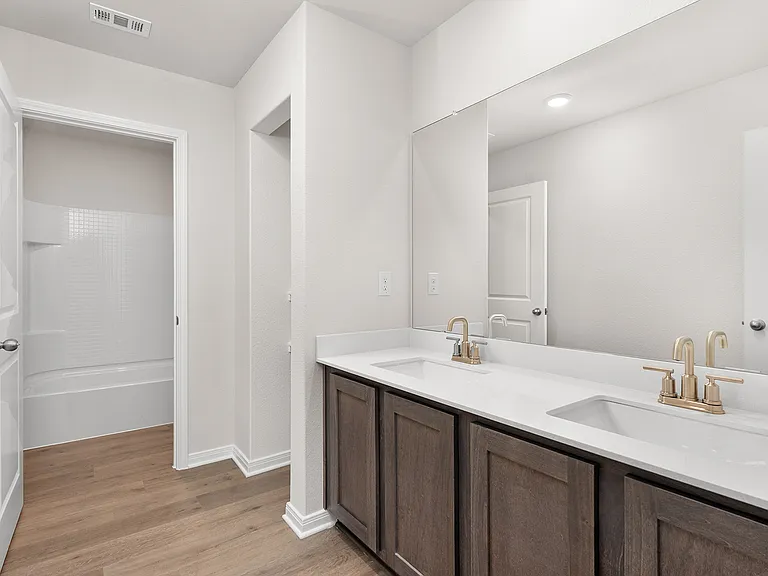 The secondary bathroom has a sprawling dual-sink vanity and a shower-tub combo.