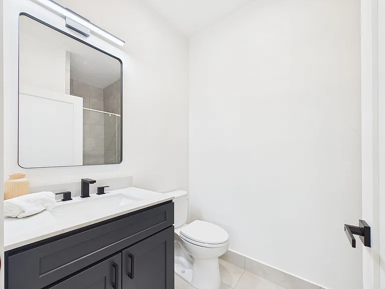 Clean bathroom with a vanity sink, large framed mirror, and shower/tub combo finished with tile surrounds.