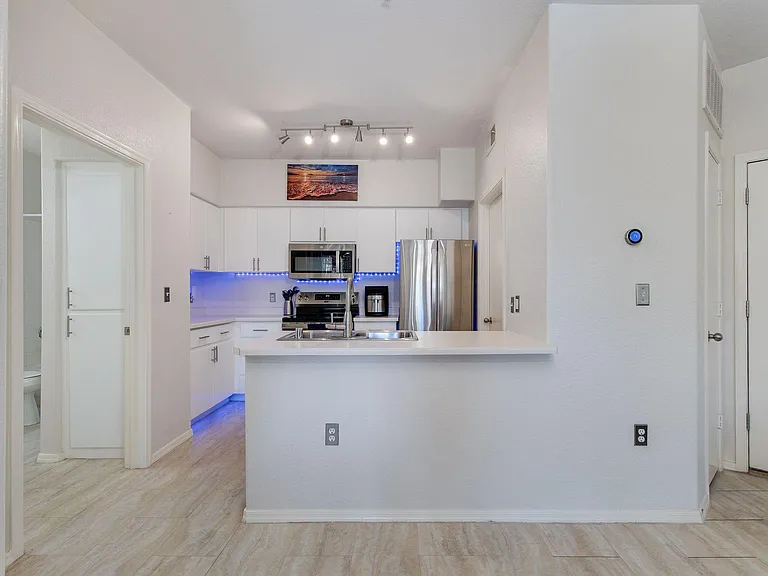 Updated kitchen with stainless appliances, ample white cabinetry, and a breakfast bar with sink for easy meal prep.