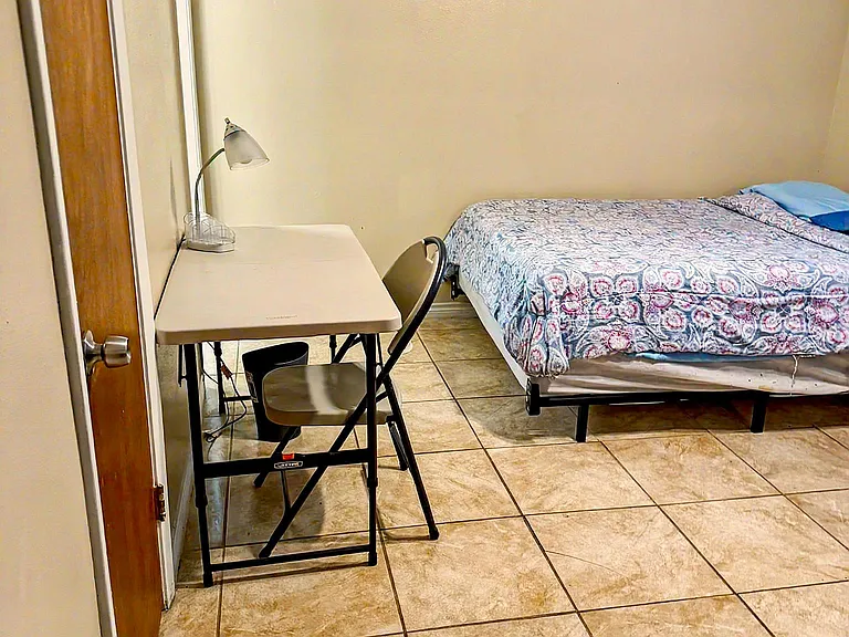 Private bedroom with tile flooring, a twin bed, and a compact desk setup for studying or remote work.