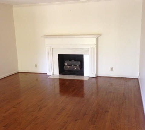 Large living room with faux fireplace and triple window over
