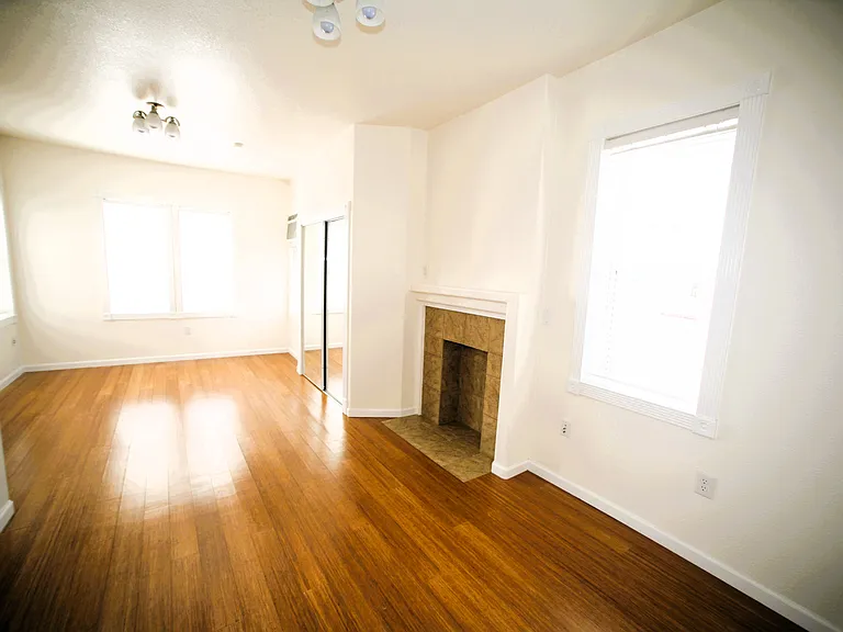 Spacious layout looking toward the bedroom area, showing the excellent flow and bright natural light. Kitchen is out of sight and to the left.