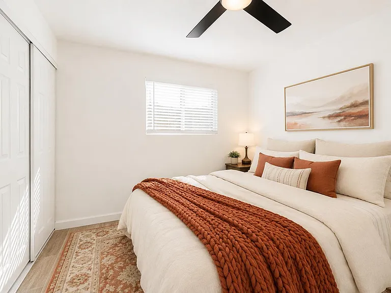 Well-appointed bedroom with a comfortable bed, ceiling fan, and a sliding-door closet for convenient storage.