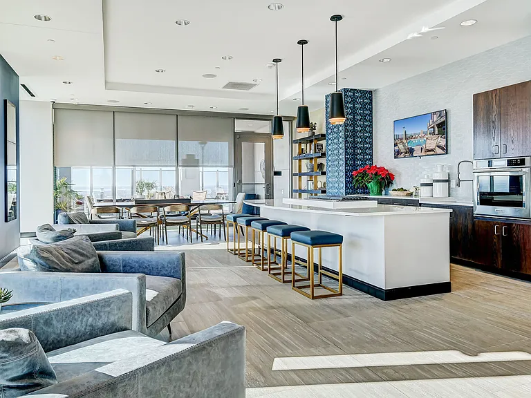 Resident lounge area with bar top seating, catering kitchen, lounge seating, entertainment area, and rooftop pool access