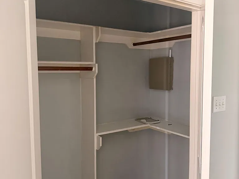 Walk-in closet with built-in shelving and double hanging rods, offering versatile storage for clothing and accessories.