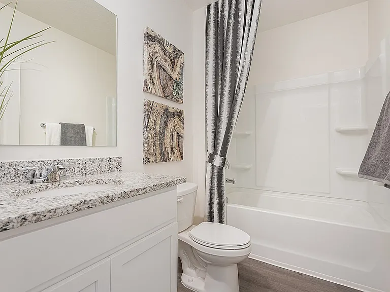Modern bathroom featuring elegant granite countertop, sleek white cabinetry, and stylish gray accents for a contemporary feel.