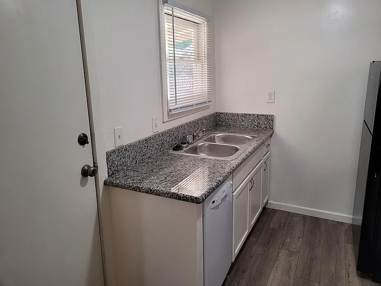 Stainless steel kitchen sink with granite counter top. Door to covered porch.
