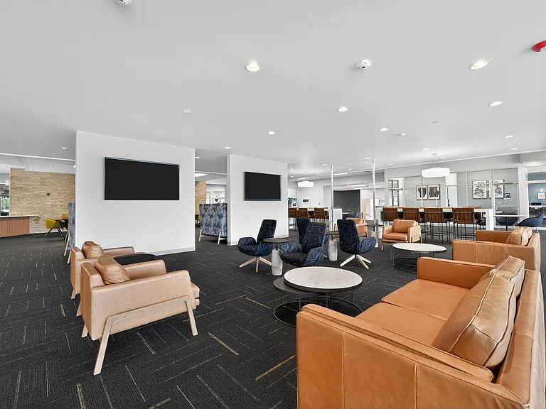 Modern and spacious lounge area featuring chic leather seating, contemporary decor, and ample natural lighting, perfect for relaxation and social gatherings.