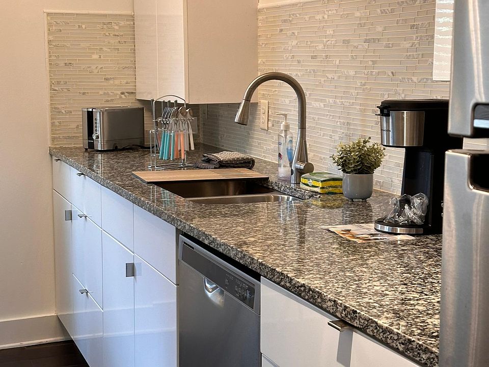 Kitchen with granite countertop, Dishwasher, Refrigerator, Coffee maker, Toaster, Utensil, and slow cooking pot.