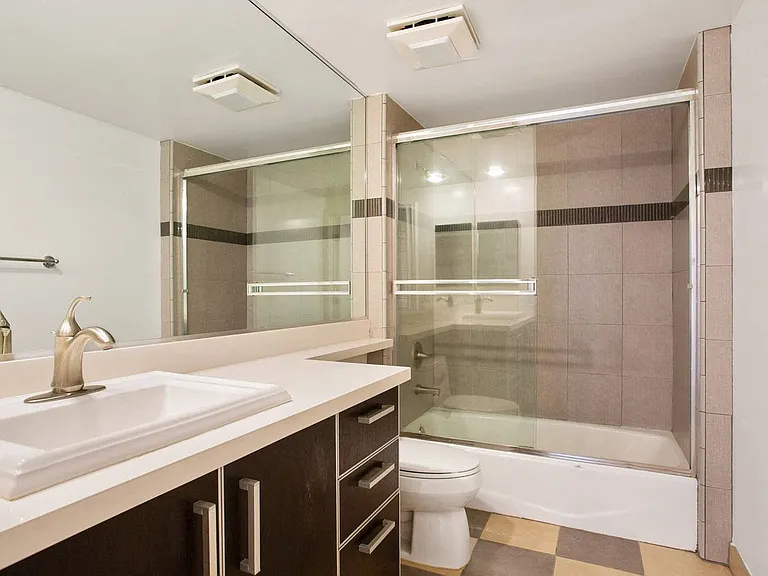 Bathroom with Bathtub with Glass Doors and Cabinet Storage