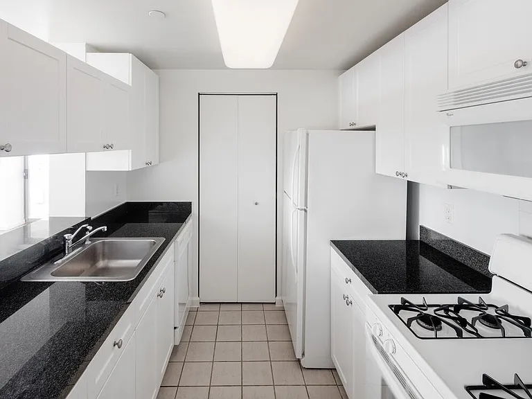 Classic Package I kitchen with white appliances, white cabinetry, black granite countertops, and tile flooring