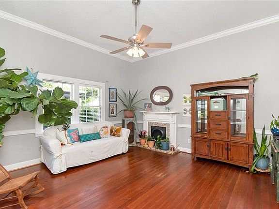 Spacious living area featuring polished wood flooring, high vaulted ceilings, and a decorative fireplace with a mantel