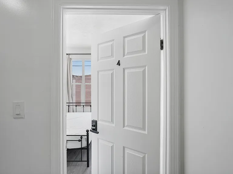 Private bedroom with a large window, curtain rod, and durable flooring, offering a comfortable setup for rest and study.